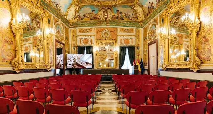Salón del Palacio de Santoña preparado para un evento, con sillas rojas y decoración dorada